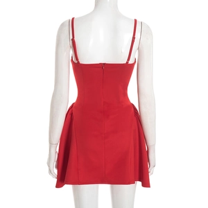 Detail view of red mini dress with thin straps, back zipper, and side ruffle pleats