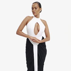 Detail of white halter neck top with teardrop cutout paired with a black pleated maxi skirt