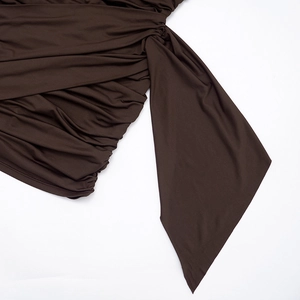 Detail view of ruched deep brown fabric with elegant draped ribbon and smooth texture