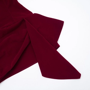 Détail de la robe en velours bordeaux avec ourlet asymétrique et finitions soignées