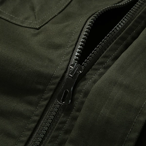 Detail of dark olive cotton jacket showing heavy-duty resin zipper and metal slider
