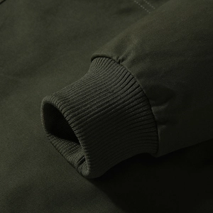 Close-up of olive green cotton jacket showing ribbed cuff and twill fabric texture