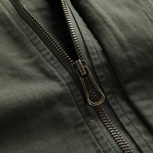 Makrodetail eines antiken Bronze-Metallreißverschlusses an olivgrüner Baumwolljacke