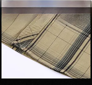 Dettaglio delle cuciture rifinite e resistenti su una camicia a quadri kaki da uomo