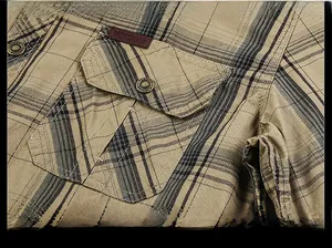 Dettaglio di camicia a quadri kaki con taschino sul petto ed etichetta in cuoio