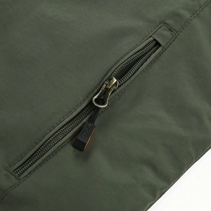 Dettaglio della tasca con zip della giacca invernale verde oliva con tirante sportivo