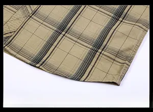 Dettaglio di camicia a quadri kaki che mostra le cuciture precise sull'orlo inferiore