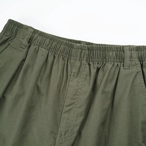 Detail of olive green cargo pants featuring elastic waist with belt loops and stitching