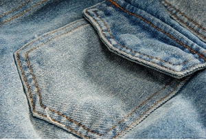 Dettaglio di giacca di jeans blu chiaro con patta della tasca e cuciture arancioni