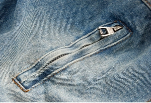 Dettaglio del tessuto denim azzurro con cerniera in metallo e cuciture rifinite