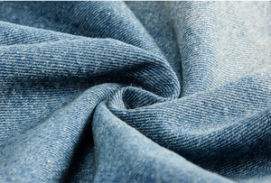 Macro di tessuto denim blu lavato con trama a saia e pieghe morbide della giacca