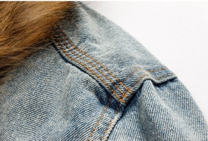 Dettaglio della giacca di jeans con caldo collo di pelliccia e cuciture gialle rinforzate