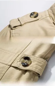 Detailed macro view of khaki trench coat showing epaulettes and marble resin buttons