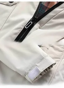 Dettaglio della giacca con cerniera metallica, polsini in velcro e fodera scozzese