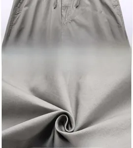 Detail of grey cotton trousers featuring an adjustable drawstring waist and fine fabric texture
