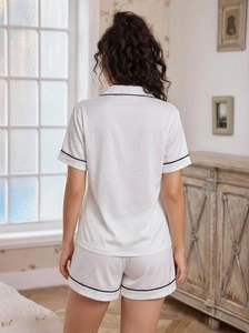 Detail of white women's loungewear set with black contrast piping and soft satin texture