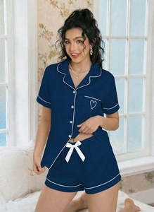 Detail of navy blue pajama set featuring white piping and minimalist heart chest embroidery