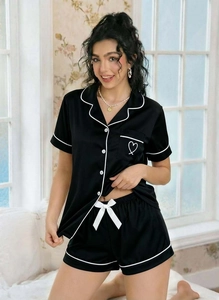 Close-up of black satin pajama set with contrast white piping and heart pocket detail