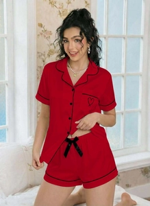 Detail of red short sleeve pajama top with black piping and heart embroidery on pocket