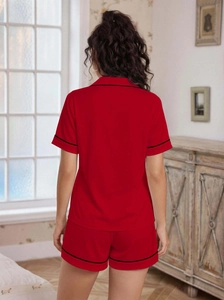 Detailed back view of red women's pajama set with black piping in a cozy room