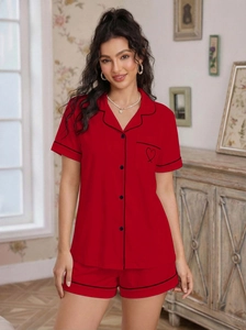 Detail of red summer pajama set with black piping and heart embroidery on the pocket