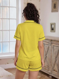 Back view of bright yellow pajama set with short sleeves and black contrast piping detail