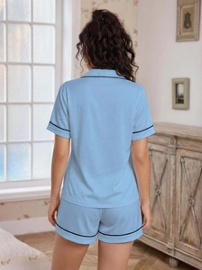 Detail of light blue pajama set featuring black contrast piping and soft fabric