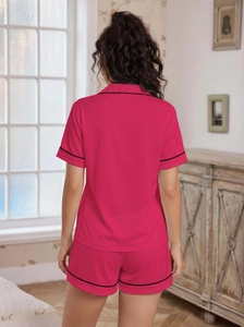 Detailed back view of pink short sleeve pajama set with black trim in home setting