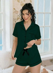 Detail of green pajama set with contrast piping and heart embroidery on the pocket