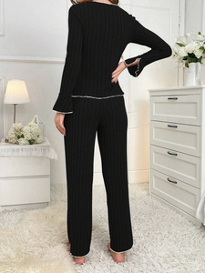 Rear view of black ribbed knit lounge set featuring contrast white stitching and bell sleeves