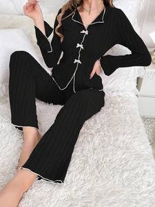 Detail of black fleece pajama set with white bows and striped textured fabric