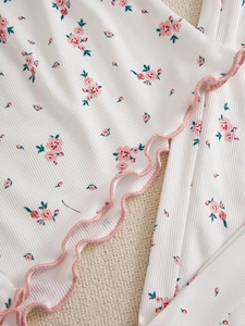 Detail of white ribbed fabric with pink floral print and delicate ruffled edges on sleepwear