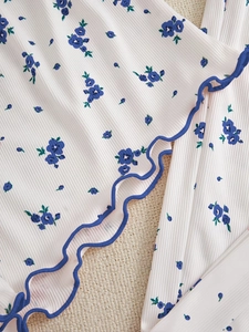 Detailed macro view of white ribbed floral fabric with blue ruffle trim for pajama set