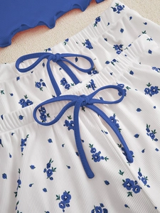 Detailed close-up of floral ribbed fabric with blue bows and lettuce trim edges