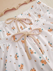 Detail of floral pink shorts with ribbed texture and decorative khaki drawstring bow