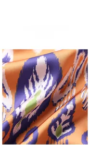 Macro detail of satin fabric featuring ethnic Ikat geometric patterns in orange and green