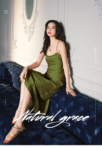 Detail of sage green satin slip dress with smooth texture on a blue velvet sofa