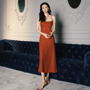 Detail of elegant rust red satin slip dress showing draped neckline and silky texture
