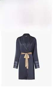 Detailed view of navy satin robe featuring golden piping and patterned cuffs with tie belt