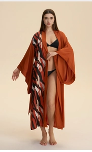 Close-up of long burnt orange kimono robe with wide sleeves and abstract stripe patterns