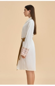 Detailed embroidery on cuffs of a white satin robe with a matching dark brown waist tie