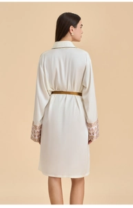 Detailed view of cream silk robe sleeves with vintage embroidery and gold waist tie
