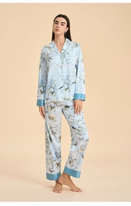 Detail view of floral and bird print on light blue silk-texture pajama set for women