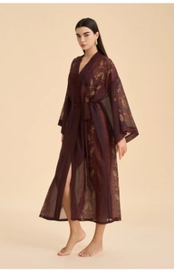 Detail of burgundy satin chiffon robe showing golden ethnic leaf print and soft texture