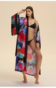Detail of vibrant tie-dye satin robe featuring bold artistic patterns and black trim