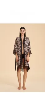 Détail d'un peignoir en satin léopard avec des pompons marron et des manches de kimono