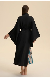 Detail of the back view on a black satin robe featuring artistic wave patterns and wide sleeves