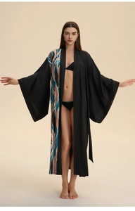 Detailed view of women's long satin robe with wavy abstract print on black fabric