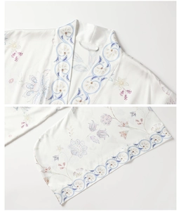 Detailed view of floral pattern and blue embroidered trim on white silk kimono robe