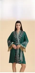 Détails de broderie florale et franges dorées sur un peignoir en soie vert foncé